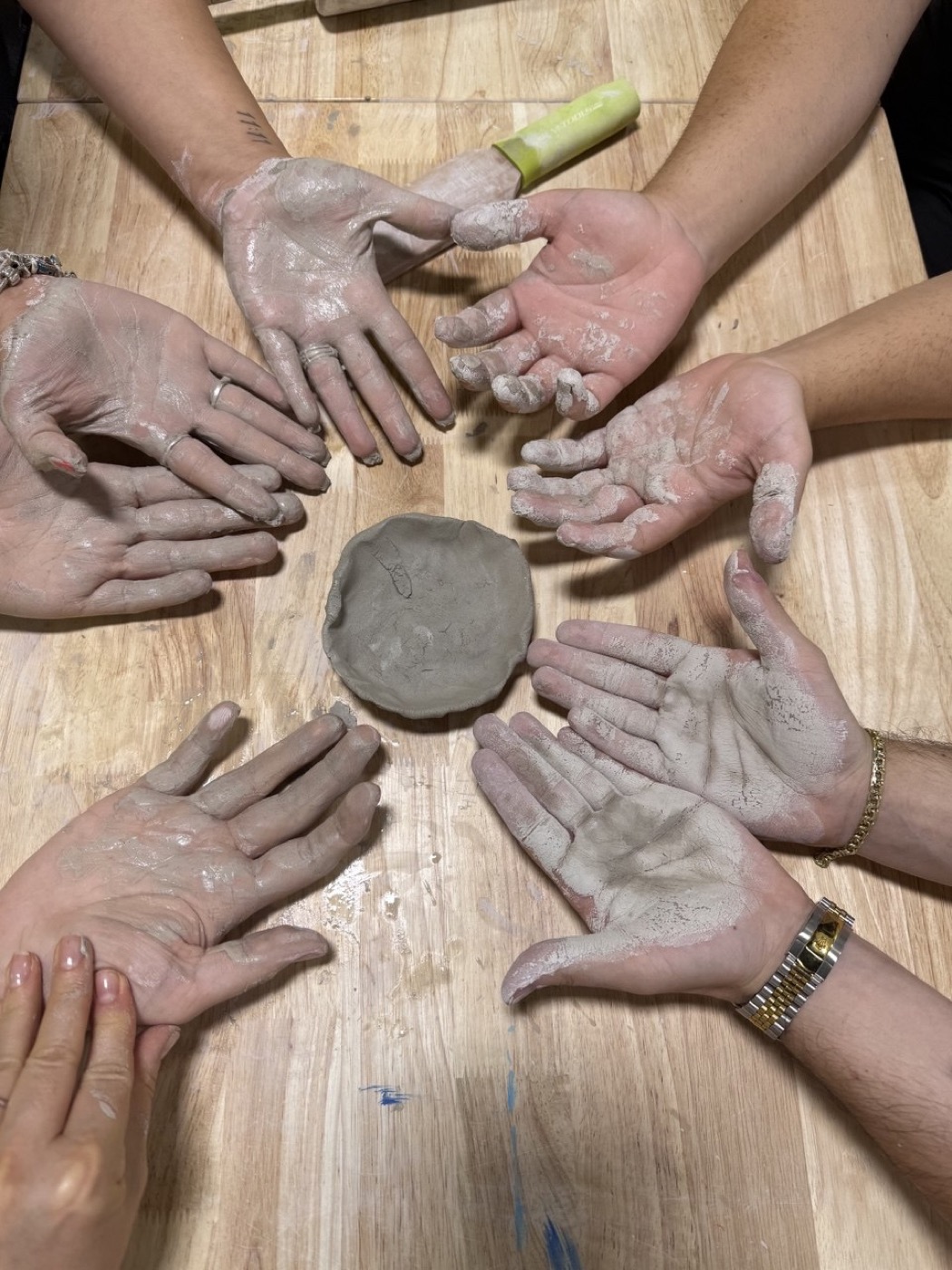 Clay-covered hands in a circle — sensory-friendly pottery class, Glendale